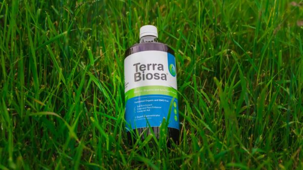 A bottle of Terra Biosa placed amidst a lush garden, symbolizing its use in agricultural settings.