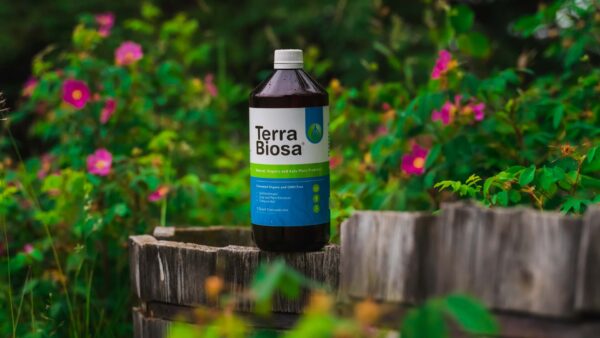 A bottle of Terra Biosa placed amidst a lush garden, symbolizing its use in agricultural settings.