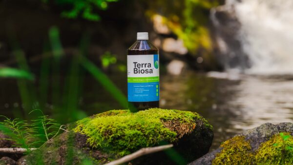 A bottle of Terra Biosa placed amidst a lush garden, symbolizing its use in agricultural settings.