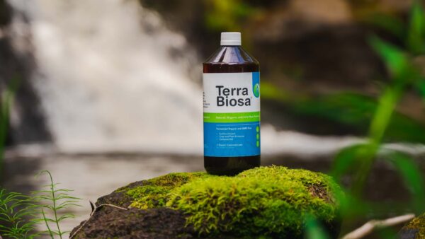 A bottle of Terra Biosa placed amidst a lush garden, symbolizing its use in agricultural settings.