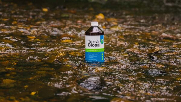 A bottle of Terra Biosa placed amidst a lush garden, symbolizing its use in agricultural settings.