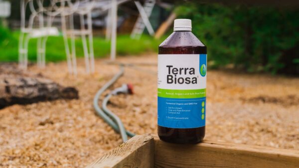 A bottle of Terra Biosa placed amidst a lush garden, symbolizing its use in agricultural settings.