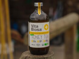 Bottle of Vita Biosa Honey Tea surrounded by tea leaves and honeycomb, highlighting its natural ingredients and refreshing appeal.